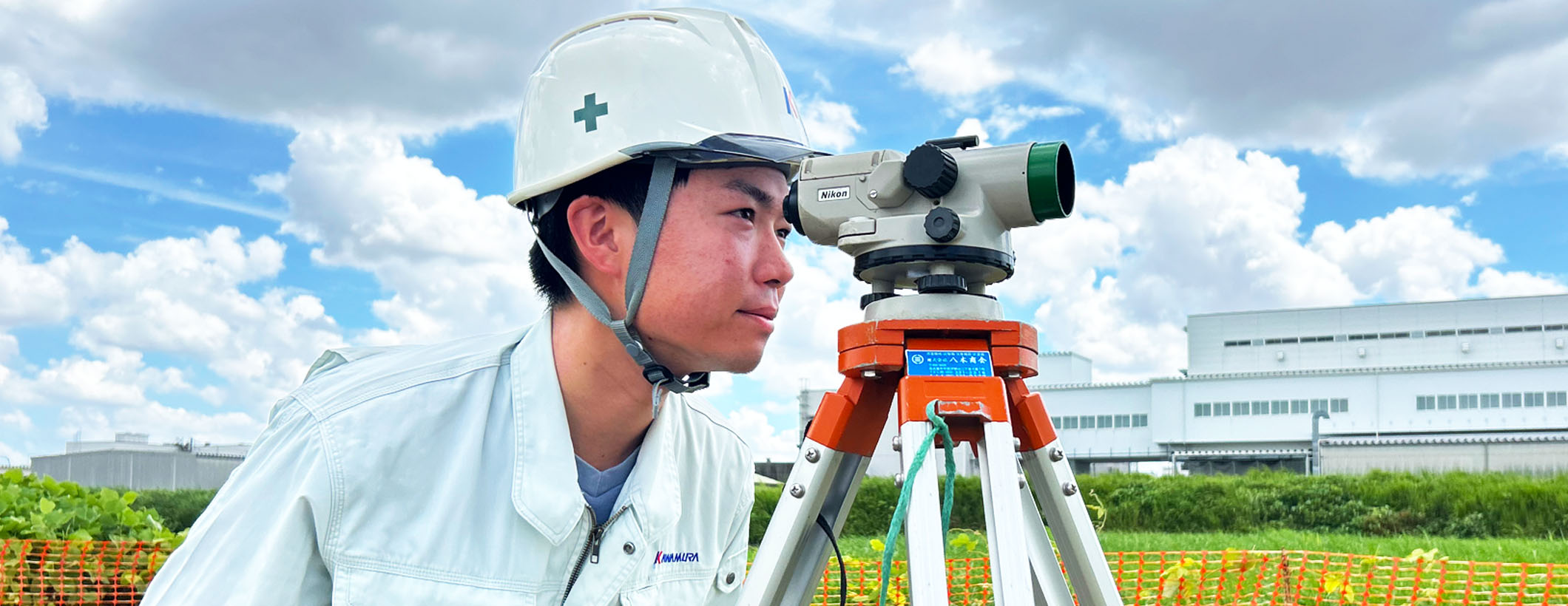 測量機器のレンズを覗く建設事業部の作業員